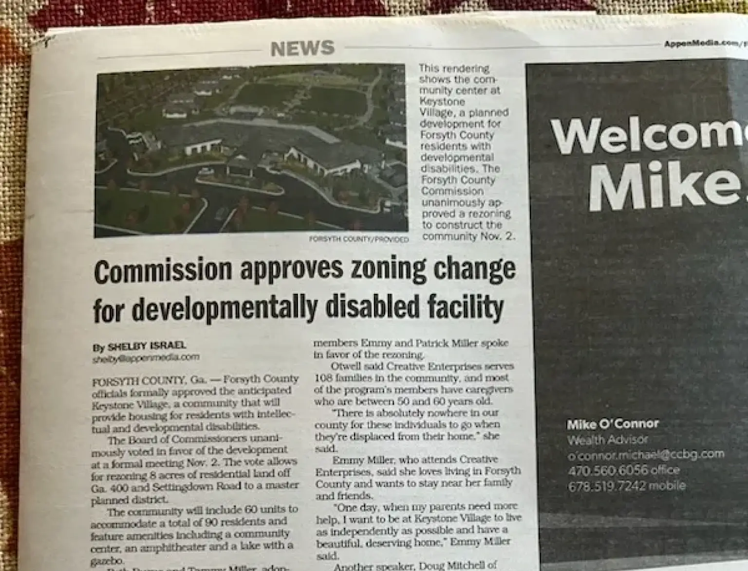 A photograph of a newspaper article from AppenMedia.com titled "Commission approves zoning change for developmentally disabled facility." The report by Shelby Israel details the Forsyth County Board of Commissioners' unanimous vote on November 2 to approve the Keystone Village project.
